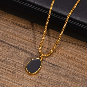 Detailed close-up of an irregular gold pendant with black enamel on a box chain