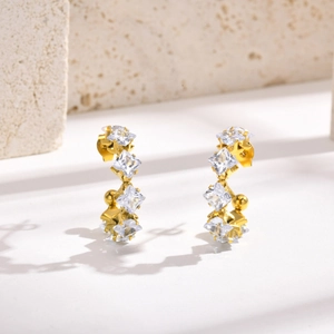 Dettaglio di orecchini a cerchio a C placcati oro 18k con zirconi quadrati incastonati