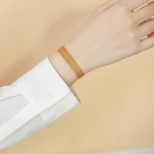 Close-up of golden mesh bracelet on wrist with elegant white shirt cuff detail