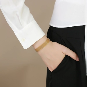 Elegant gold mesh stainless steel strap bracelet worn by a model in casual attire