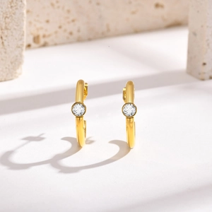 Detail of 18K gold-plated C-shaped earrings with a bezel-set round zircon stone