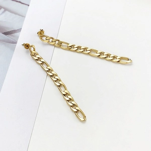 Detailed close-up of gold Figaro chain tassel earrings with minimalist geometric lines