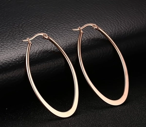 Detailed macro view of rose gold large oval hoop earrings on a black leather texture