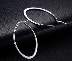 Detailed close-up of polished silver oval hoop earrings with secure click-top closure