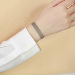 Close-up of silver stainless steel mesh bracelet worn with a white shirt cuff