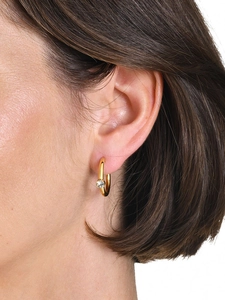 Macro shot of 18K gold plated C-shaped earrings with zircon on a model ear