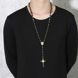 Detailed view of religious cross necklace with black beads and gold medals on model