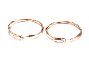Macro detail of large rose gold twisted hoop earrings with mobius spiral design