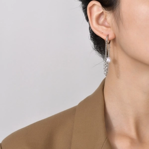 Detail of silver stainless steel chain tassel earrings with white pearl on a model