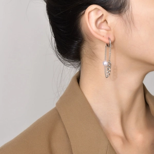 Detailed view of silver chain tassel earrings with white pearl accent on a female model