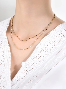 Double-layer gold chain necklace with black and white bead accents on female model