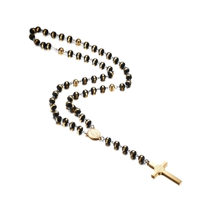 Golden St. Benedict cross necklace with black beads and religious medal on white background