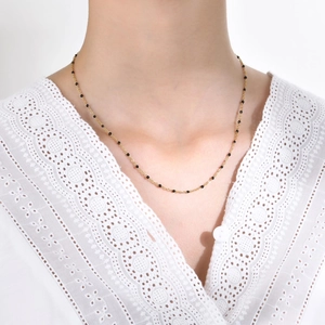 Golden stainless steel necklace with black beads shown on a female model neck