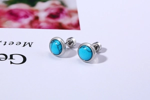 Close-up of stainless steel turquoise stud earrings with natural black marble texture