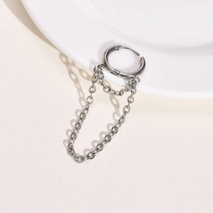 Macro detail of silver stainless steel chain earrings hanging on a white porcelain dish