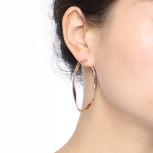 Close-up of model wearing rose gold twisted Mobius hoop earrings in polished steel