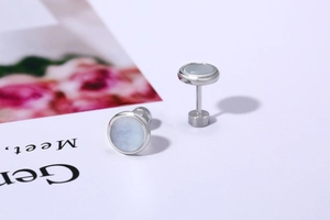 Detail view of round stainless steel stud earrings with blue stones and screw back closure