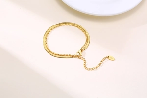 Detail of golden double-layer snake and bead chain bracelet with K18 engraved tag