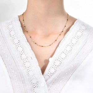 Golden stainless steel chain necklace featuring delicate black and white beaded accents