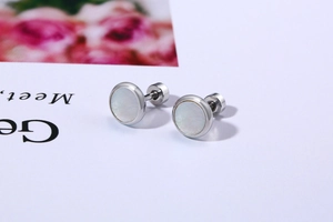 Detailed macro view of silver stainless steel earrings with iridescent white shell inlay
