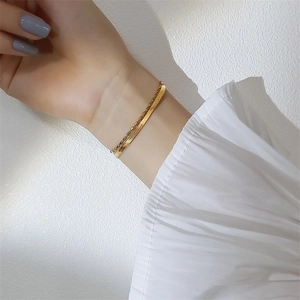 Close-up of double-layer gold snake and bead bracelet worn on a woman's wrist