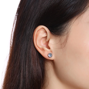 Close-up of a silver stainless steel turquoise earring on a model ear lobe