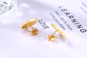 Vue macro de boucles d'oreilles arbre de vie dorées avec fermoirs papillon sur carte
