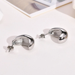 Detailed view of silver thick curved half-moon stud earrings with high-polished surface