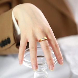 Macro detail of 18k gold plated ring with square green zircon on woman's hand