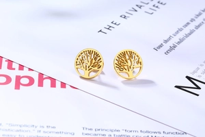Gros plan sur les boucles d'oreilles arbre de vie dorées avec motif ajouré sur magazine