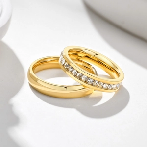 Macro shot of gold-plated titanium couple rings with smooth surface and pavé-set crystals