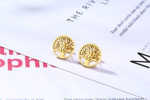Vue détaillée de boucles d'oreilles arbre de vie dorées sur un magazine minimaliste