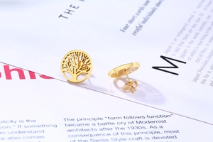 Détails des boucles d'oreilles arbre de vie dorées sur fond de magazine élégant