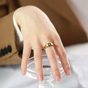 Detail of 18K gold plated titanium steel ring with emerald green zircon on model hand