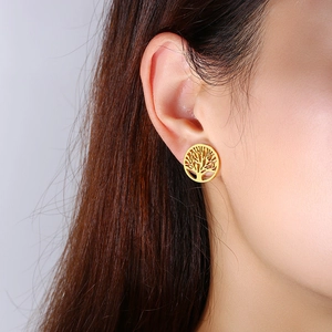 Gros plan de boucles d'oreilles arbre de vie dorées portées pour montrer les détails