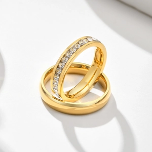 Detail of gold titanium steel couple rings showing one plain band and one with paved zircons