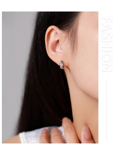 Vue détaillée de boucles d'oreilles huggie en argent avec cœur en zircon