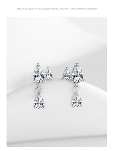 Detailed view of silver drop earrings with shimmering cubic zirconia on white silk