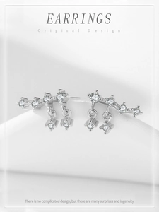 Macro shot of 925 silver fringe earrings with cubic zirconia star tassels on white