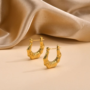 Detail of gold bamboo texture earrings on champagne satin showing tiered craftsmanship