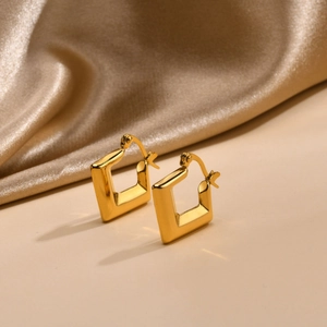 Close-up of golden U-shaped bamboo earrings on luxury champagne satin fabric