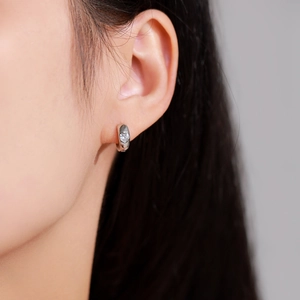 Boucle d'oreille créole en argent 925 avec zircon en cœur portée par un modèle
