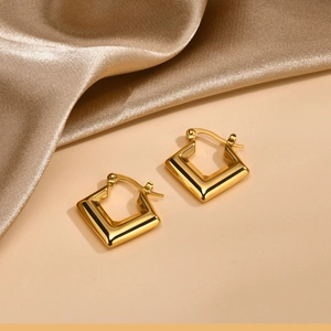 Detail of gold U-shaped hoop earrings with polished bamboo texture on satin
