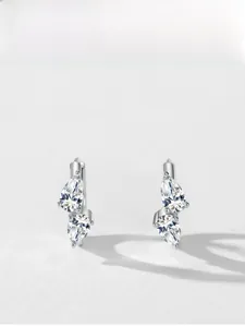 Detail view of pear-cut zircon earrings with silver drop shapes on white background