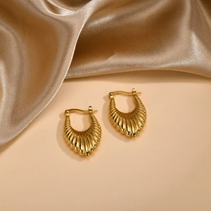 Detail of gold U-shaped hoop earrings with bamboo texture on elegant silk background