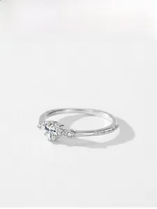 Gros plan de la bague en argent avec pierre en cœur et anneau à texture ondulée