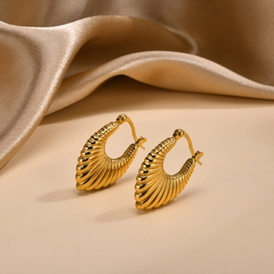 Close-up of golden U-shaped croissant hoop earrings with a textured bamboo stripe finish