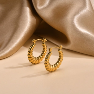 Detail of gold U-shaped hoop earrings with bamboo texture on champagne silk fabric
