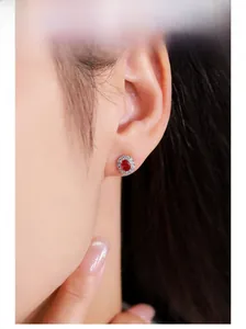 Detailed view of luxury red zircon earrings with halo diamonds on a female model