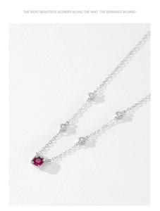 Detail of 925 silver necklace with red corundum pendant and white zircon accents